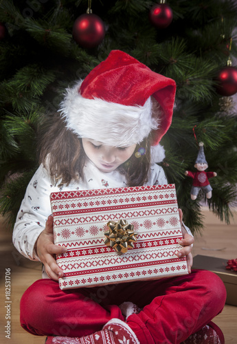 Little girl opening he present under Christmas tree photo