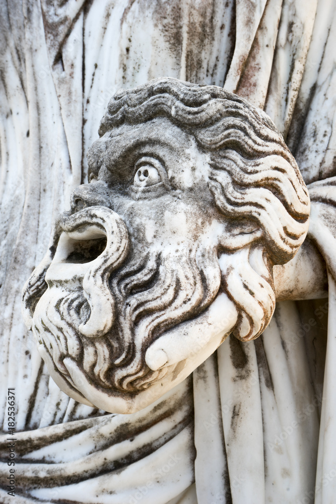 A tragic mask in the hand of Statue of Melpomene, the muse of tragedy, on Achillion palace, Corfu Greece.