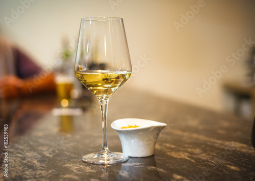 Glass of white wine on bar with small bowl of tapas photo