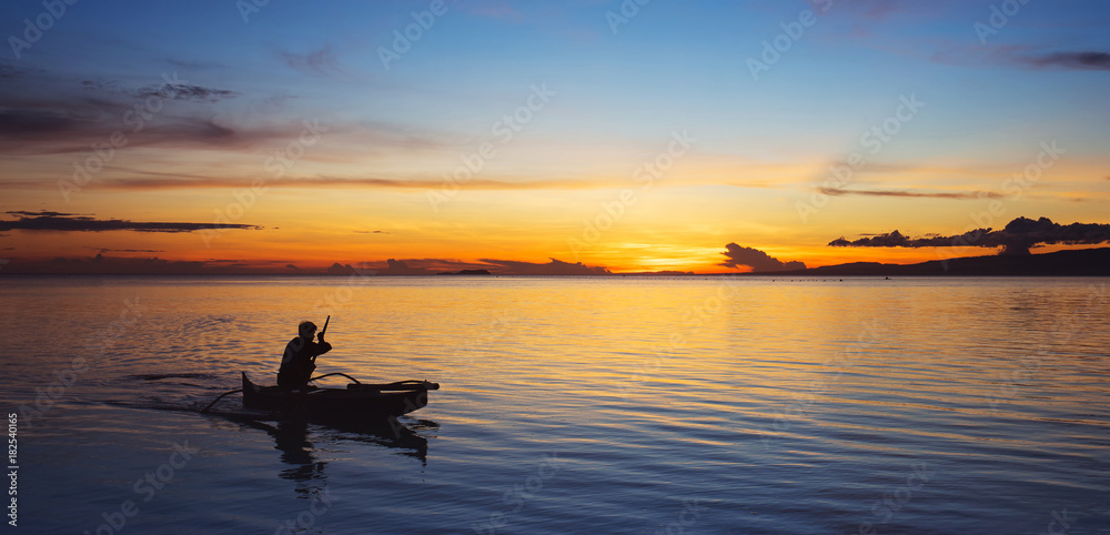 Fisherman on small boat on the sea at sunset. Banner