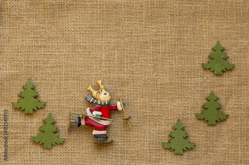 Elch auf Schlittschuhen verkleidet als Weihnachtsmann mit Tannenbäumen auf Jute