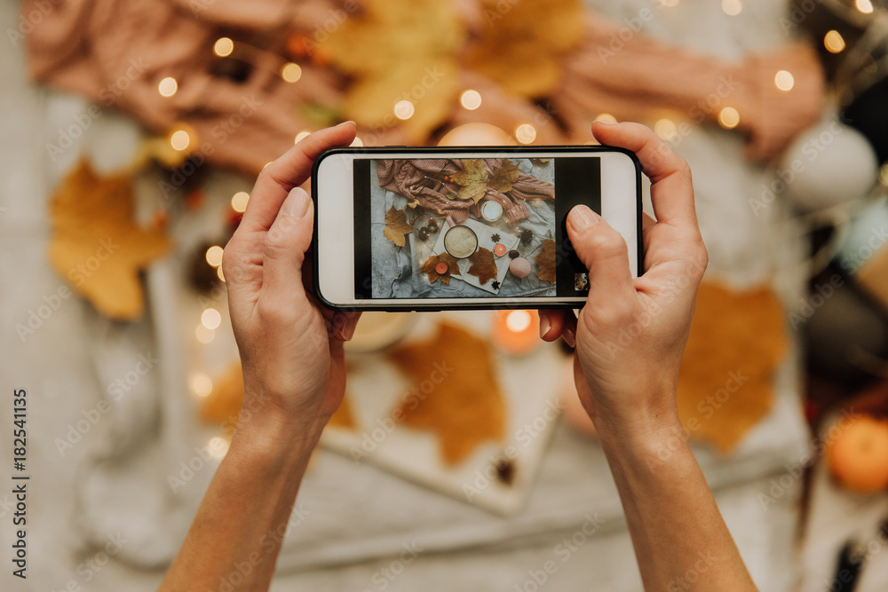 Instagram photography blogging  concept. hand holding phone taking photo of stylish winter flat lay. cozy mood autumn.
