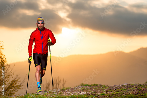 Man athlete practicing trail with sticks at sunset