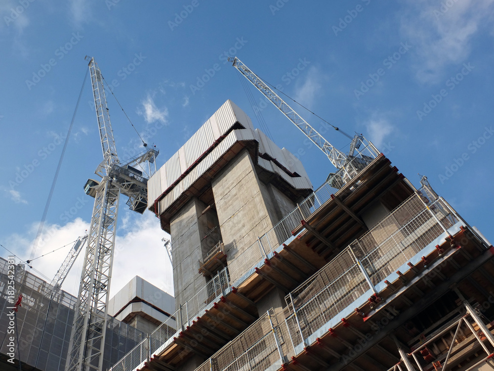 cranes and construction machinary working on a large development site with concrete service core