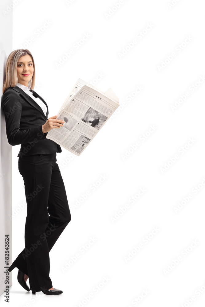 Formally dressed woman with a newspaper leaning against a wall Formally dressed woman with a newspaper leaning against a wall