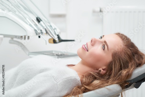 Shot of a young cheerful woman waiting for medical examination at the dentist office sitting in a dental chair smiling looking away copyspace health smile teeth medicine professional dentistry.