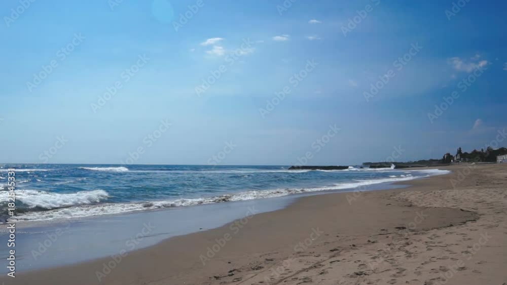 A deserted beach stretching away with foamy ocean waves coming to the dark sand. Canggu, Bali, Indonesia. A deserted beach stretching away with foamy ocean waves coming to the dark sand. Canggu, Bali, Indonesia.