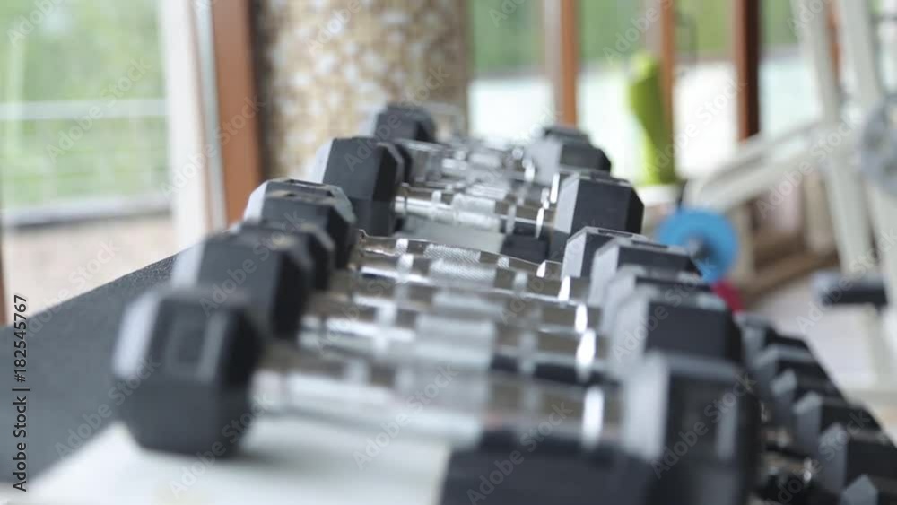 Female hands choosing dumbbells on the rack in gym. Female hands choosing dumbbells on the rack in gym.