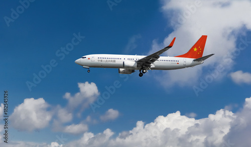 Commercial airplane with Chinese flag on the tail and fuselage landing or taking off from the airport with blue cloudy sky in the background