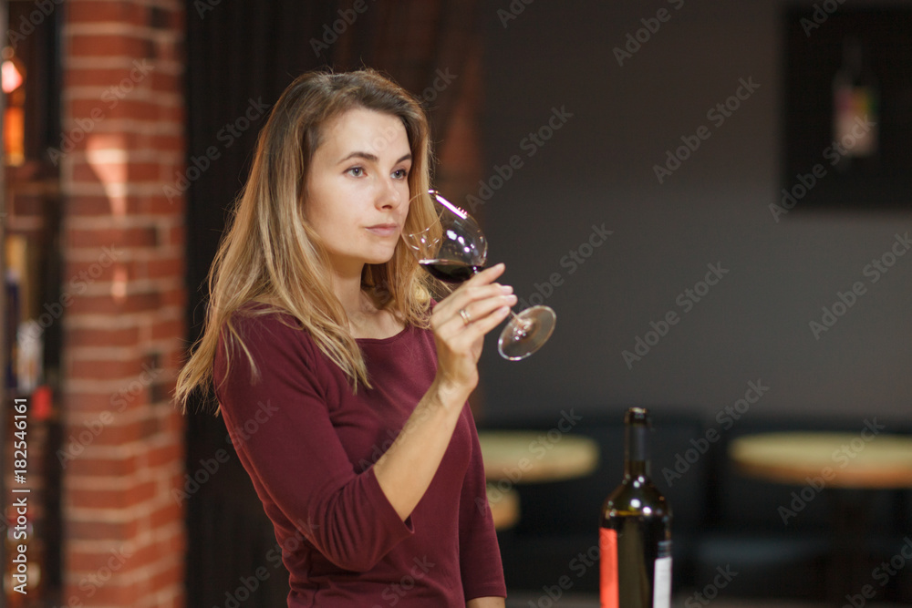 Attractive woman taste red wine in the restaurant