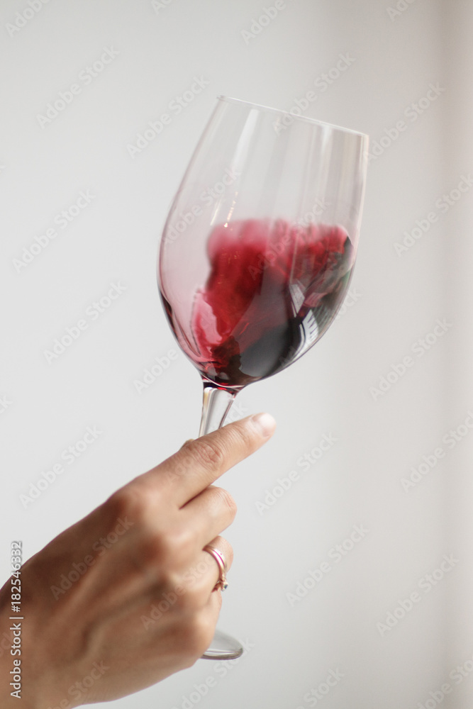 Woman's hand check red wine on grey background - obrazy, fototapety, plakaty 