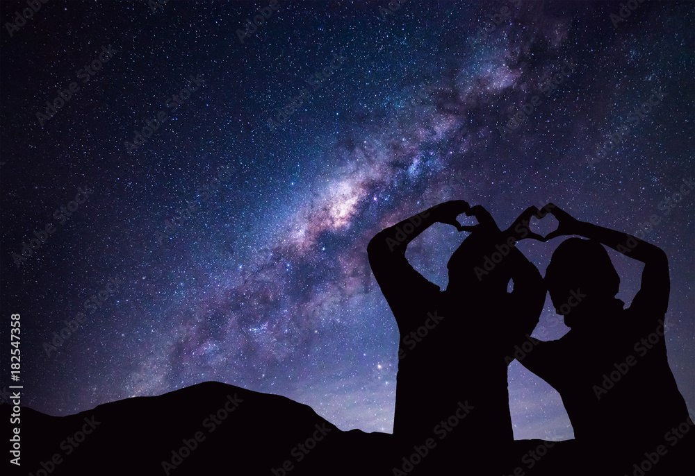 People makes heart symbol by hand with Milky Way and night sky on background.