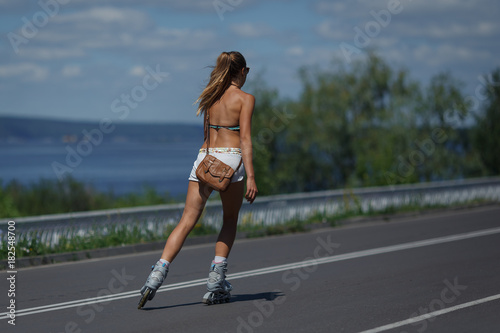 back view of young girl in shorts and tops skates on roller skates