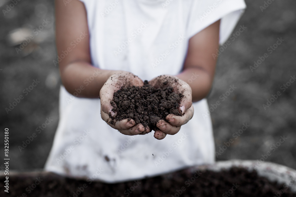 Φωτογραφία Little child girl holding black soil in hand for planting