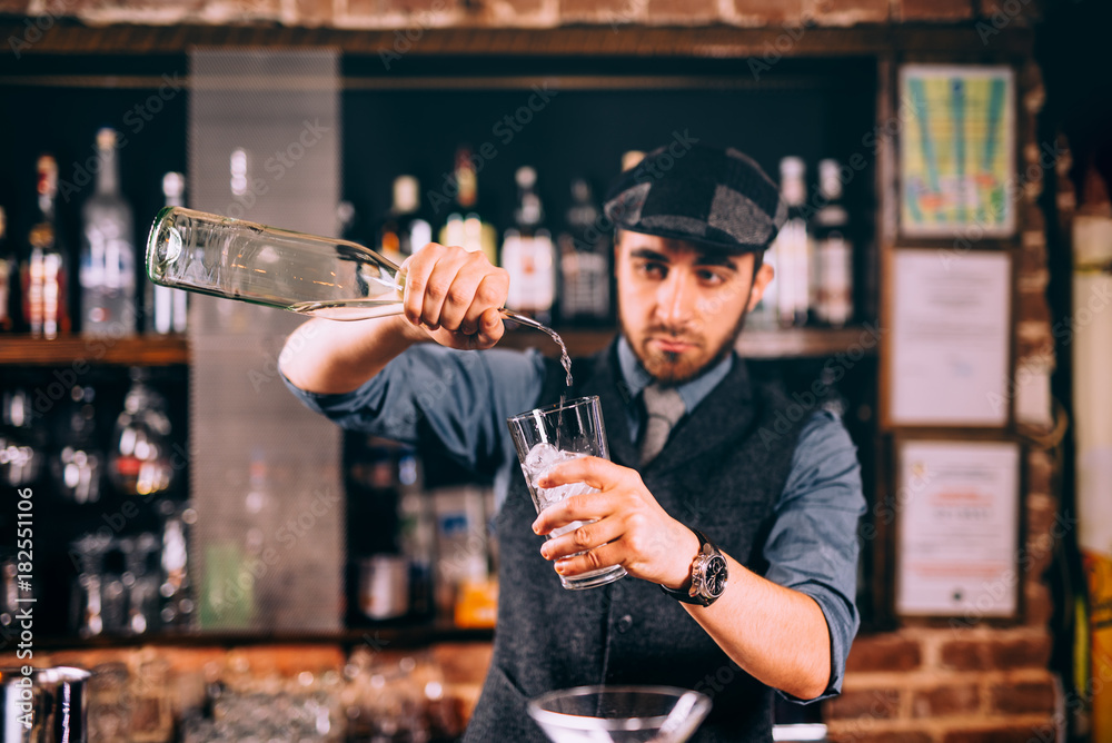 Professional bartender pouring rum into cocktails at bar, pub or restaurant