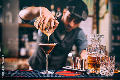 Portrait of professional bartender preparing alcoholic drinks at bar
