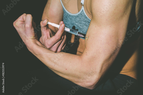 Steroids, Young woman inject anabolic steroids in her muscles doping in sport concept. photo