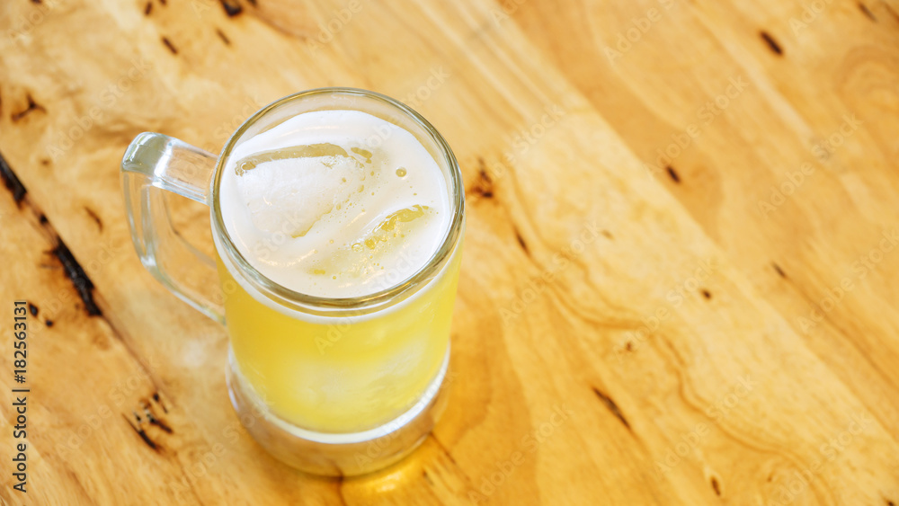 A glass of beer on a wooden table.