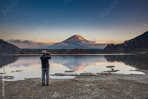 A man take photo on mountain Fuji at Kawaguchiko lake in japan with blue cloud sky
