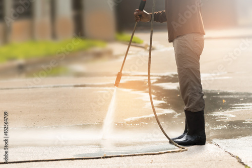 High pressure deep cleaning.Worker cleaning driveway with gasoline high pressure washer ,professional cleaning services.