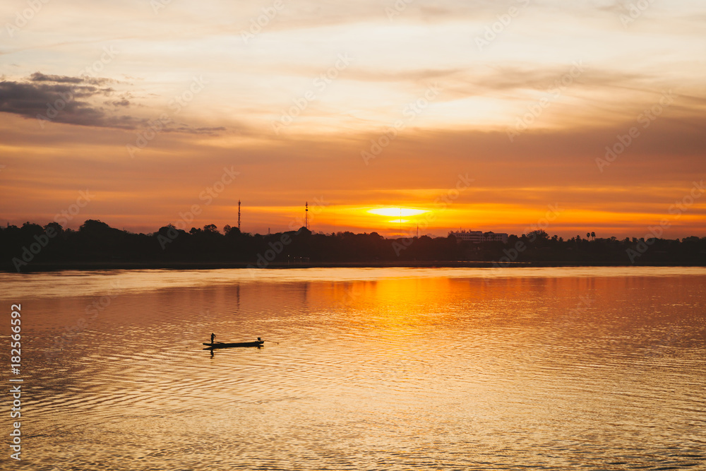 Fototapeta premium Fisherman floats on a lake at sunrise.