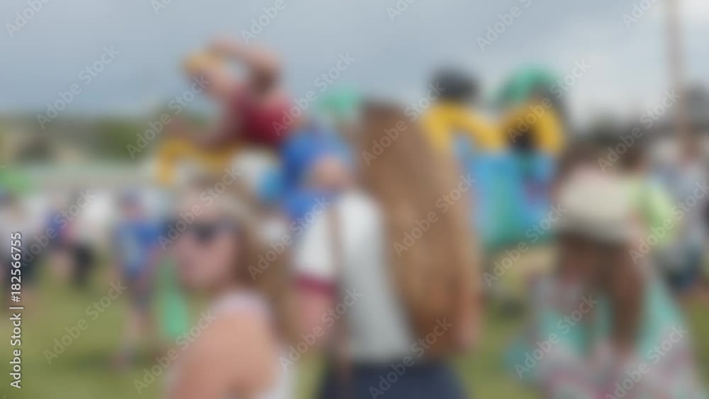 Families at a rural fair with rides and activities blurred