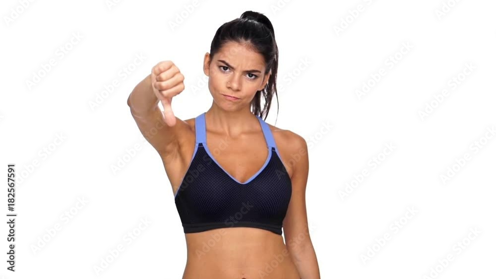Serious brunette fitness woman showing thumb down at camera over white background
Serious brunette fitness woman showing thumb down at camera over white background