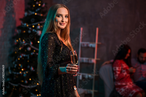 Beautiful young woman with glass of champagne at Christmas party