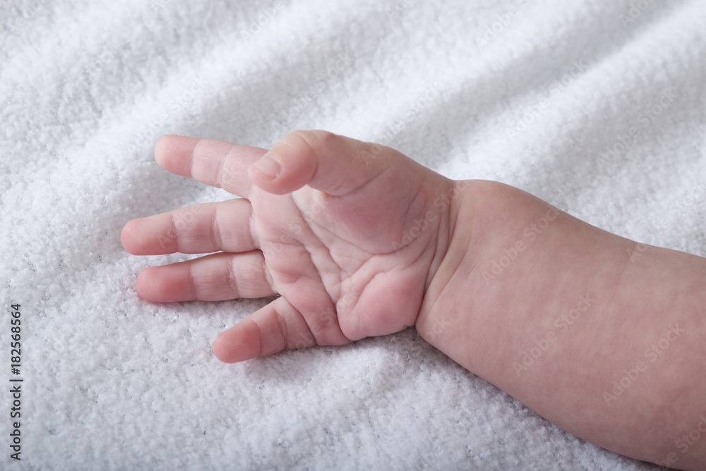 Beautiful baby hand on white soft blanket Beautiful baby hand on white soft blanket