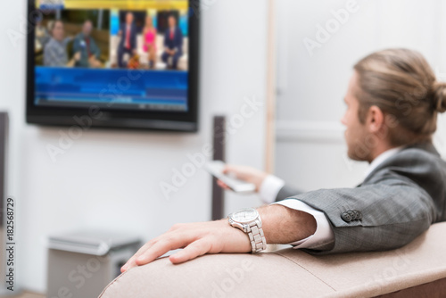 Businessman sitting at home and watching TV