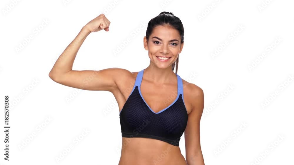 Happy brunette fitness woman showing her bicep and pointing on him while looking at the camera over white background Happy brunette fitness woman showing her bicep and pointing on him while looking at the camera over white background