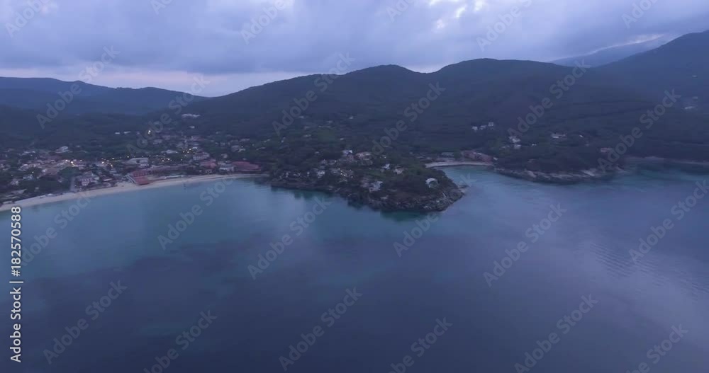 Aerial, island coast with beautiful calm sea in the evening and overcast sky