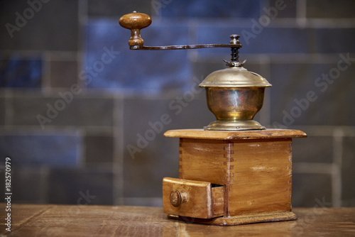 Vintage wooden coffee grinder stands on a table on a blurred background