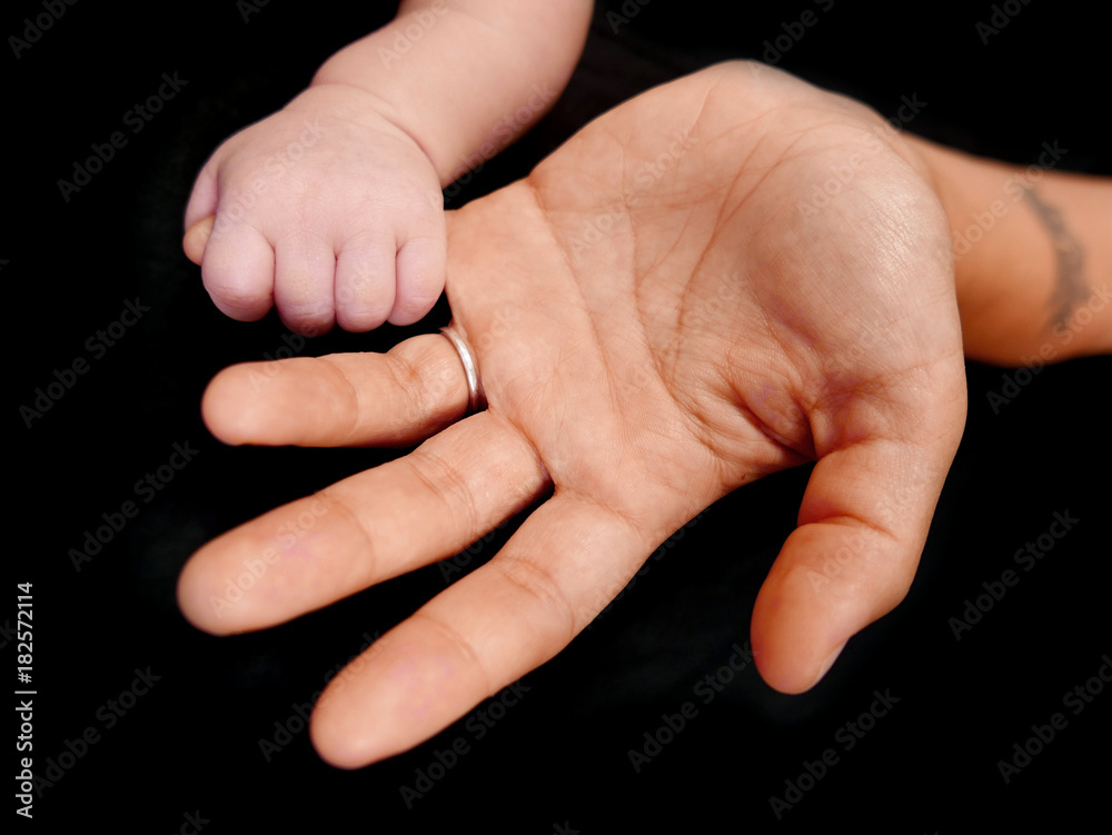 motherhand and babyhand isolated on a black background motherhand and babyhand isolated on a black background