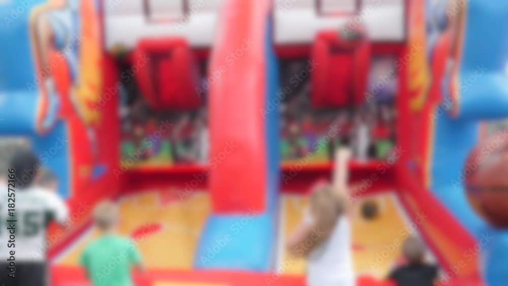 Families playing ball at a rural fair with rides and activities blurred Families playing ball at a rural fair with rides and activities blurred