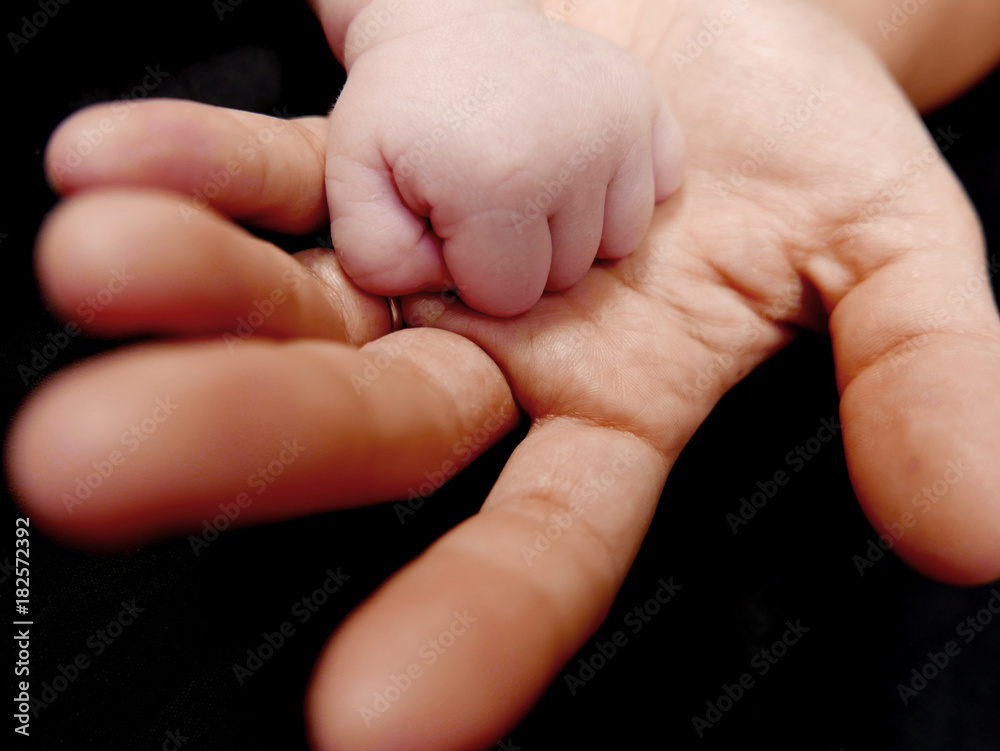 motherhand and babyhand isolated on a black background motherhand and babyhand isolated on a black background