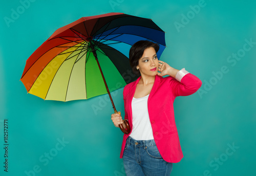Smiling girl with colorful umbrella at studio background