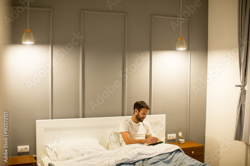 Young man reading book in bed