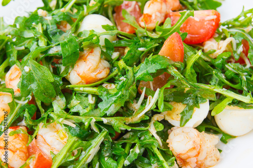 Salad with arugula and shrimp. Fresh dish with arugula, cherry tomatoes, shrimps close-up.