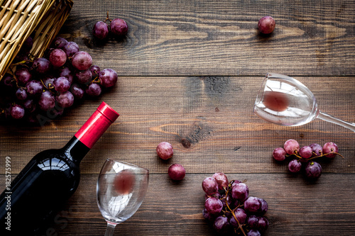 Drink wine. Bottle, glaas and grape on dark wooden background top view copyspace photo