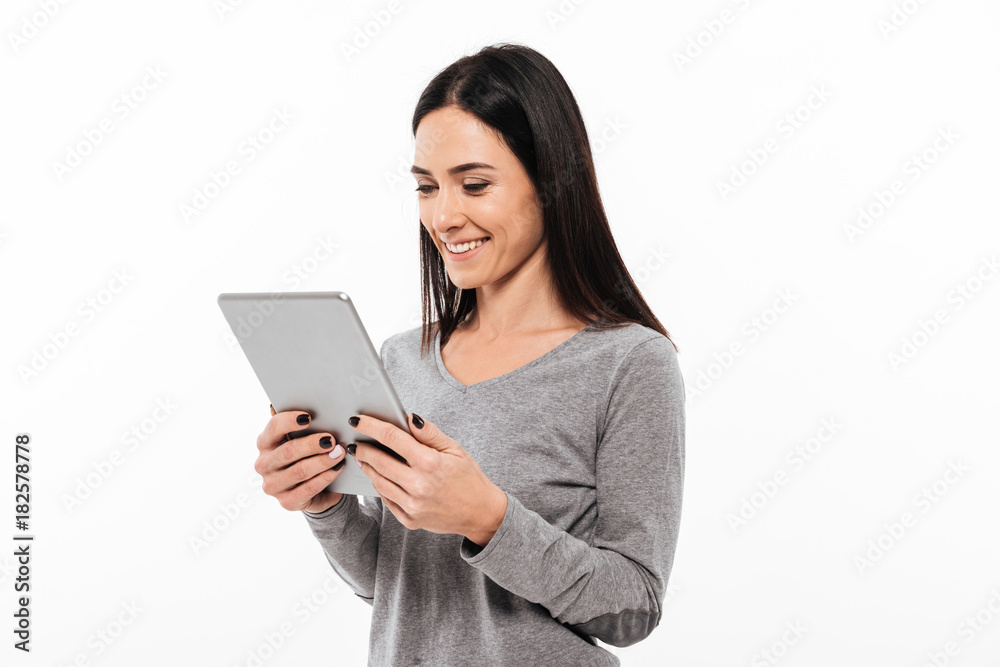 Happy woman standing isolated using tablet computer. Happy woman standing isolated using tablet computer.