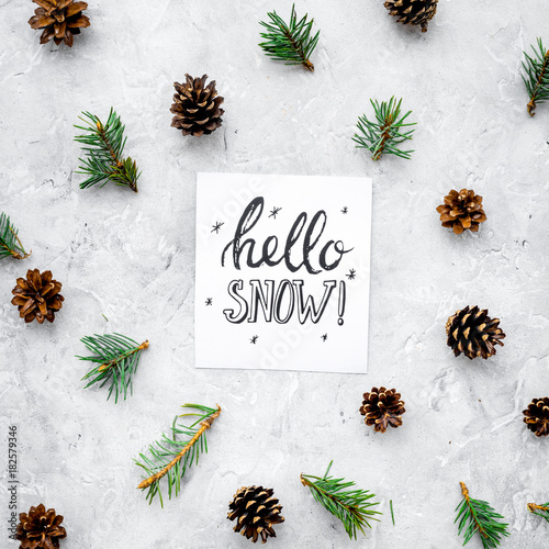 Hello snow hand lettering. Winter pattern with pinecones and spruce branch on grey background top view