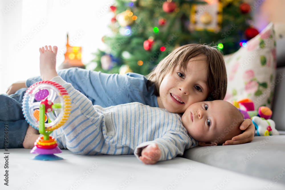Naklejka premium Six years old preschool boy, playing at home with his newborn baby brother
