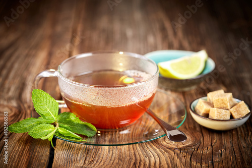 Hot cup of tea with brown sugar and lemon and mint leaves