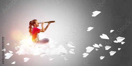 Concept of careless happy childhood with girl looking in spyglass