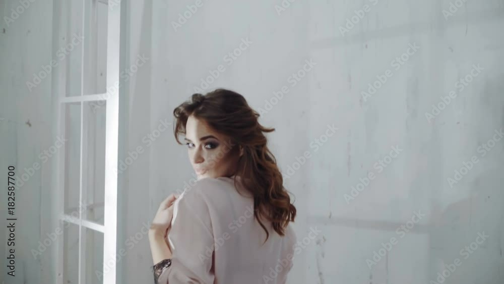 Sexy beautiful brunette woman posing in pink dressing gown. A girl with a thin thin body. Sexy beautiful brunette woman posing in pink dressing gown. A girl with a thin thin body.