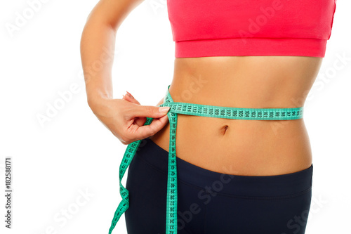 Woman measuring her waist over white background. Wellness concept.