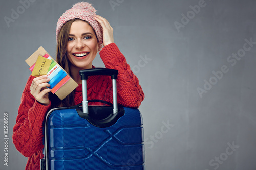 Happy woman with toothy smile holding credit card, passport and tickets for travel.
