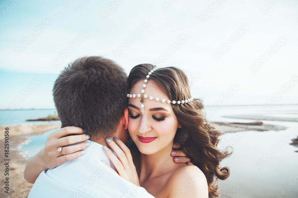 Obraz premium Young couple in love is resting together near the lake and mountains, beautiful caucasian woman and man fell in love, tenderness and hugs, straight couple against the beautiful background