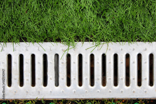 Concrete water drain or ditch on the road with green grass photo